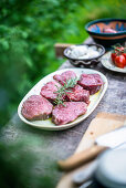 Raw beef loin steaks with ingredients in a garden kitchen
