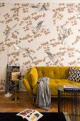Mustard-yellow sofa against patterned wallpaper in living room