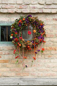 Herbstlicher Blumenkranz mit Reagenzgläsern an Backsteinwand