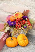 Rustikale Herbstdeko mit Blumengesteck und Kürbissen