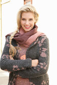 Junge blonde Frau mit Schal in grau-rosa Strickmantel