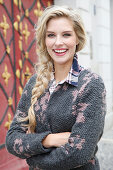 A young blonde woman wearing grey knitted coat