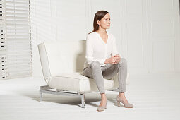 A woman sitting on a chair with her toes pointing outward (body language: 'pushing something away')