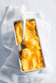 Mangoeis im Eisbehälter mit Silberlöffel
