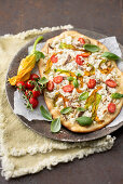 Pizza mit Ricotta, Zucchiniblüten, Pinienkernen, Anchovis und Kirschtomaten