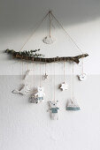 Handmade mobile with plaster figures suspended from branch in child's bedroom