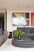 Elegante Lounge mit grauer Polstergarnitur, Designer-Couchtisch und großformatigen Fotos an der Wand