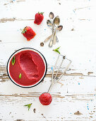 Strawberry sorbet or ice-cream with fresh berries, mint and metal scooper on over white rustic wooden backdrop