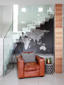 Brown leather armchair next to stairs with glass balustrade