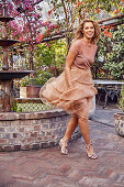 A young woman wearing a bronze-coloured blouse and skirt