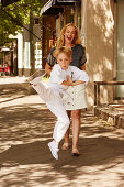 Sohn macht Karatebewegung auf der Straße, im Hintergrund stolze Mutter