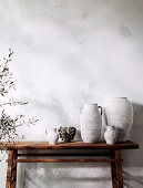 Rustic wooden console with vases and containers next to olive trees