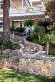 Path with natural stones leads through the palm garden to the house