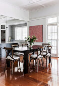 Dining table with chairs in front of a patio door in an open living area with polished wooden floor