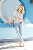 A blonde woman wearing a long-sleeved top and jeans standing in a beach cafe