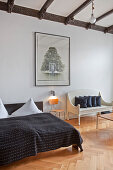 Chair and white bench next to double bed with black bedspread in bedroom