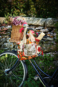 Flowers in wicker basket and baguette in floral shopping bag hung from bicycle