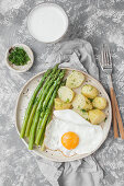 Fried eggs with dill potatoes and cooked green asparagus