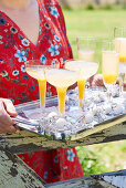 Frau hält Tablett mit Aprikosen-Bellinis und Weihnachtsdeko