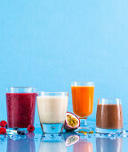 Vier verschiedene Smoothies vor blauem Hintergrund