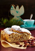 A mini cranberry and pecan nut stollen for Christmas on baking paper in front of a cup of coffee