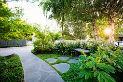 Weg mit grauen Steinplatten im üppig grünen Vorgarten