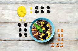 Chocolate smoothies breakfast bowl with chocolate chips, mango, blackberry, almond and Chia seeds