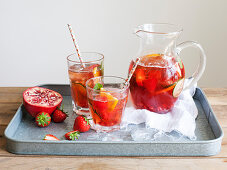 Pomegranate Pimms in jug with fruit on metal tray