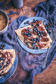 Crepes drizzled with melted chocolate and topped with blueberries