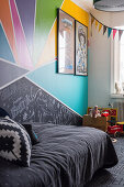 Dark bedspread on bed in child's bedroom with multicoloured wall