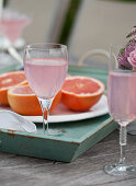Brunch outside, flowers, glasses of sparkling pink lemonade, grapefruit halves on an outdoor table