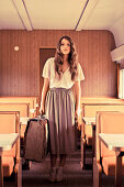 A brunette woman with a suitcase on a train