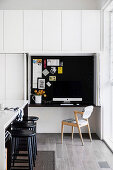 Küchentheke mit schwarzen Barhockern, Mini Home Office hinter Faltschiebeelement