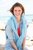 A young woman wearing a denim shirt with a blue jumper over her shoulders