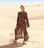 A blonde woman in the desert wearing a light summer blouse and trousers