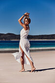 Junge Frau in weißem Kleid am Strand