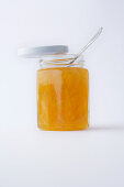 A jar of tangerine jam against a white background