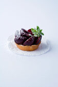 A mini tartlet with cherries against a white background