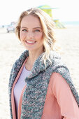 A blonde woman wearing an apricot cardigan with a jumper over her shoulders