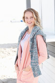 A blonde woman wearing an apricot cardigan with a jumper over her shoulders