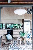 Open kitchen with light wooden front and mirrored back wall, seating area in the foreground