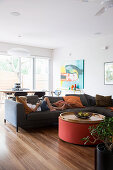 Upholstered sofa with pillows and lying boy, round coffee table, dining area in front of patio door