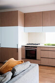 Fitted kitchen with wood-colored and white fronts in an open living room