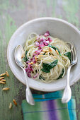 Rice spaghetti with spinach, red onions and roasted pine nuts