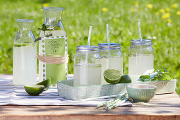 Selbst gemachte Limonade mit Limette und Minze in Schraubgläsern mit Strohhalm und in Karaffe