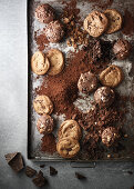 Cookies and muffins on a baking tray surronded by crumbs and chocolate