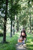Women carrying picnic basket through trees
