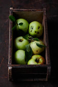 Fresh green apples in a wooden box