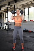 A young woman performing a thruster with dumbbells