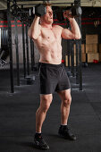 A young man performing a man maker big with dumbbells and a push press